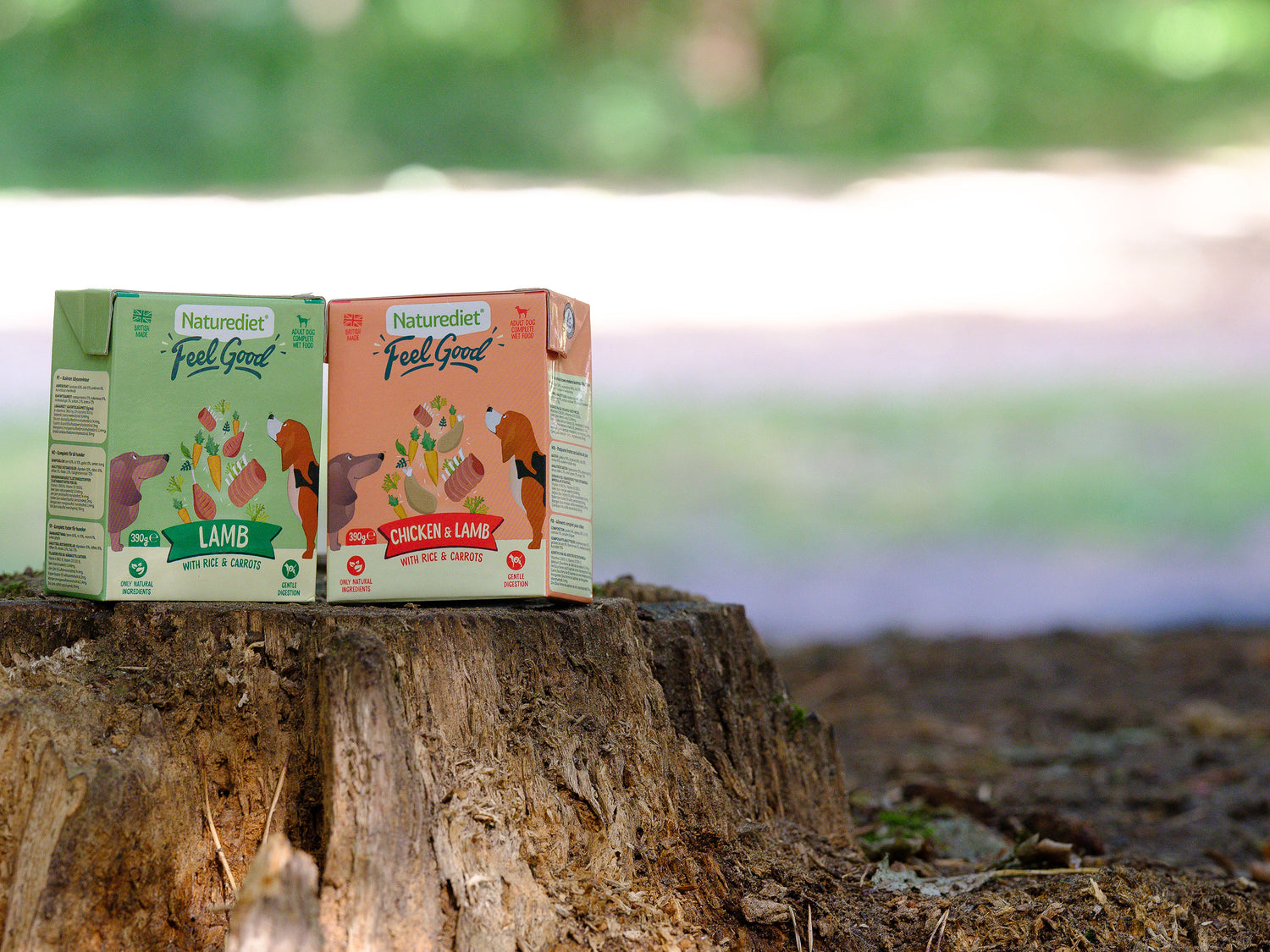 Two Naturediet 'Feel Good' pet food boxes on a tree stump with a natural background.