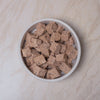 White bowl filled with chunks of Naturediet Salmon & Whitefish wet dog food on a beige surface